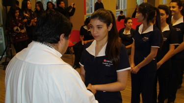 Alumnas de Enfermería recibiendo por parte del sacerdote Hernán Durán la bendición de sus manos.